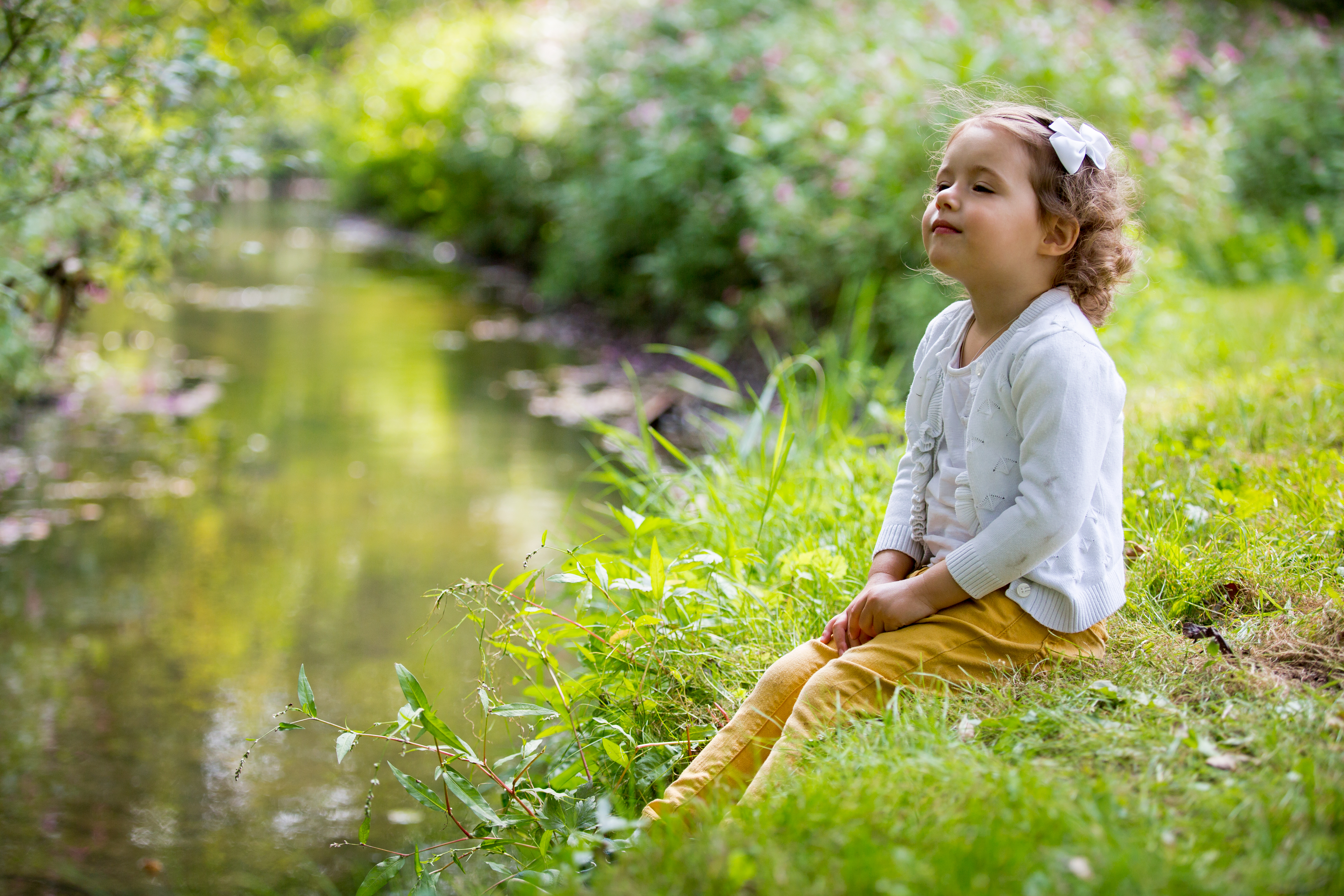 Smiling girl on riverbank sitting in green grass