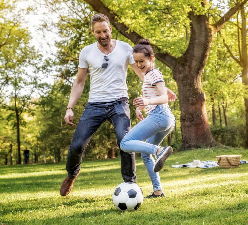 father and teenage daughter playing soccer